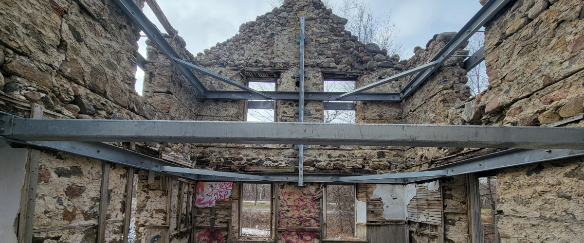 the interior of the stone ruins of a farmhouse, with metal beams supporting the structure