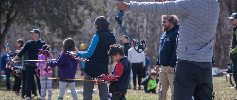 A boy puts an arrow in his bow in a line of archers participating in a Family Archery class.