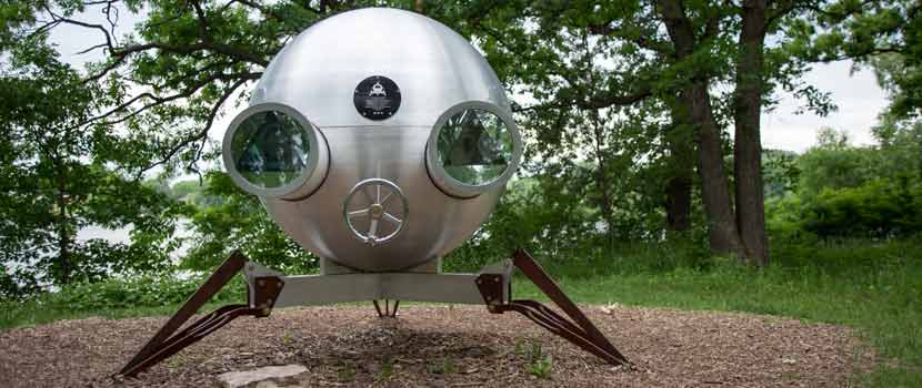 a round metal sculpture on three angled legs. It looks like a UFO.