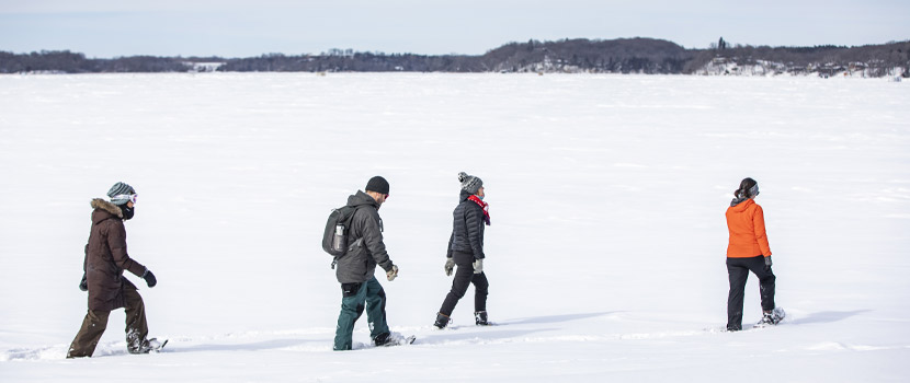 group of people snowshoeing on a snowy lake