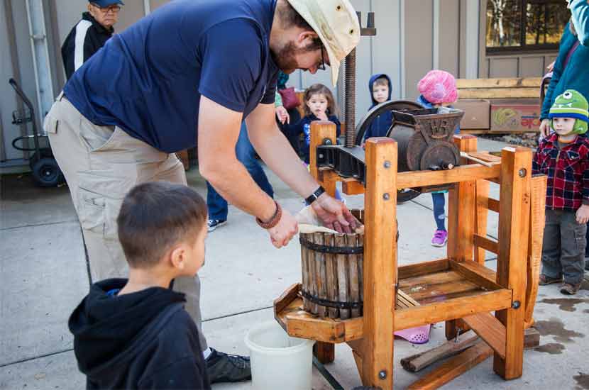 A naturalist shows children how to use a cider press.