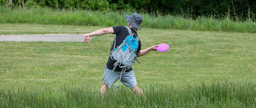 A person readies to throw a disc on a disc golf course.