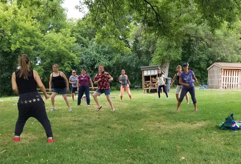 A group of women dance on a lawn outdoors.