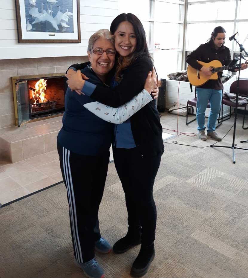 Giannina Posner and a elderly woman hug and smile at the Fish Lake Regional Park Pavilion.