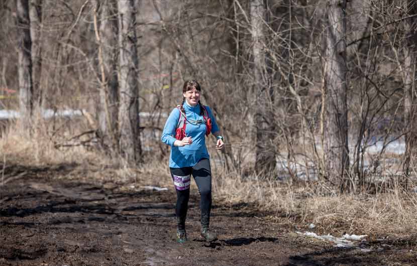 a woman running on a muddy trail