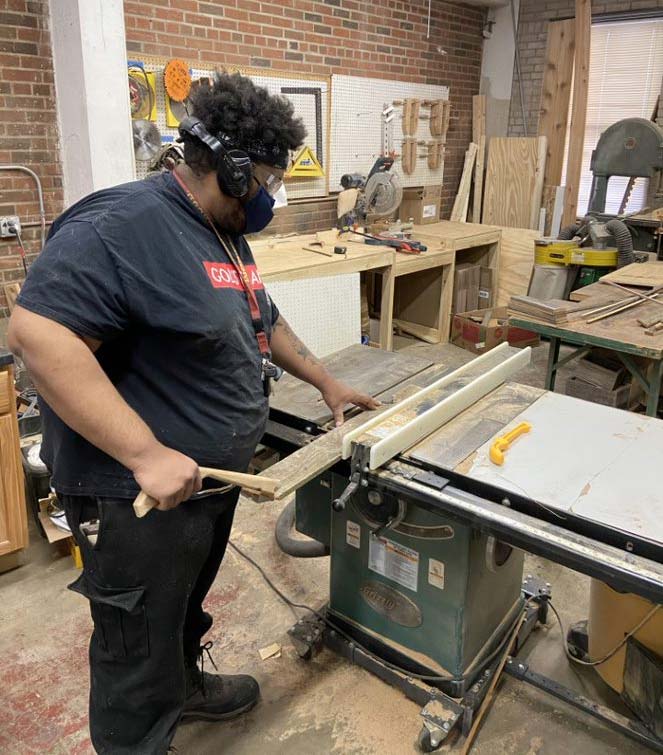 Marcellius Watley, a peer advocate at Elpis Enterprises, uses a table saw in the woodshop.