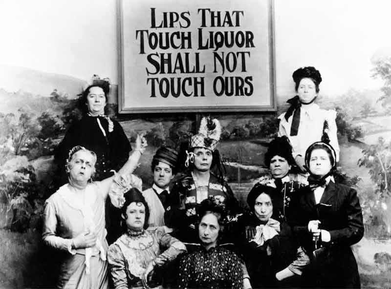 a black and white photo of 10 women holding a sign that says "lips that touch liquor shall not touch ours."