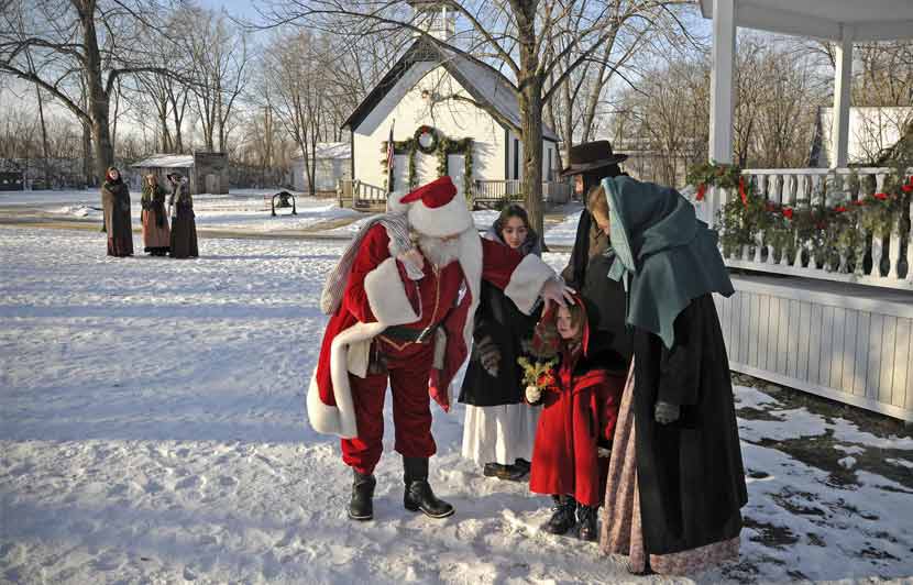 a family talking with Santa Claus outside a decorated porch