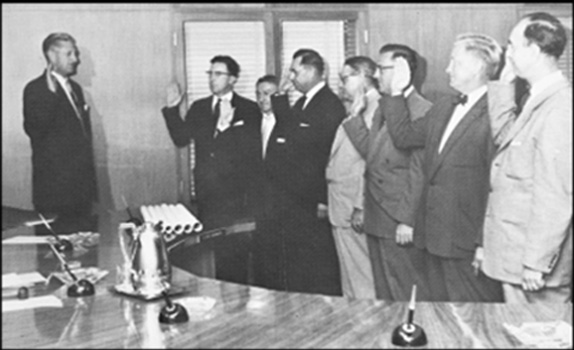 A group of men hold their right hand up as they are sworn in.