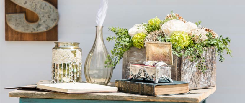 a table is set with an old book, a silver box, and some metal vases.