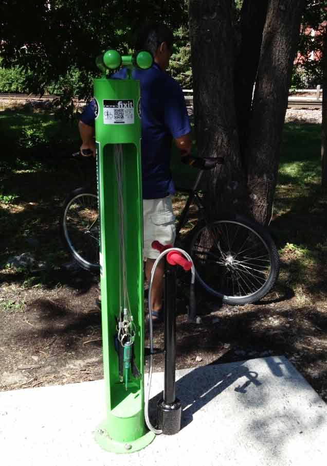 a bright green bike repair station that includes bike tools and an air pump.