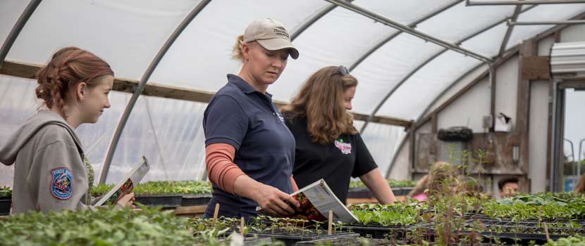 a teen girl job shadowing a woman at gale woods farm. They are standing in a green house.