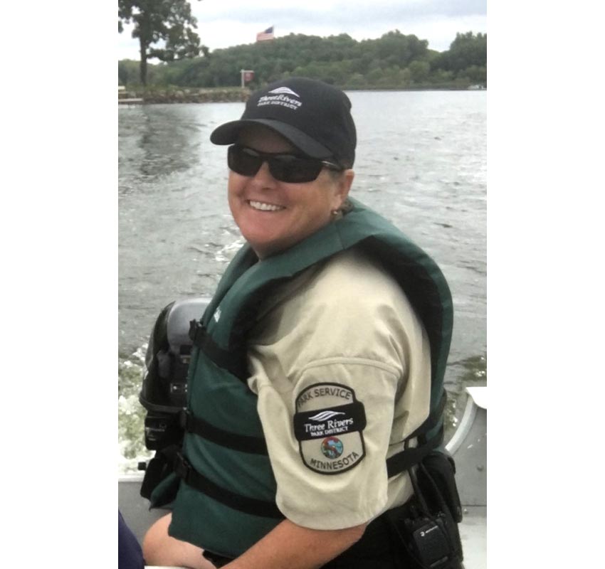Lori in her Park Service Assistant uniform on a boat on a lake.