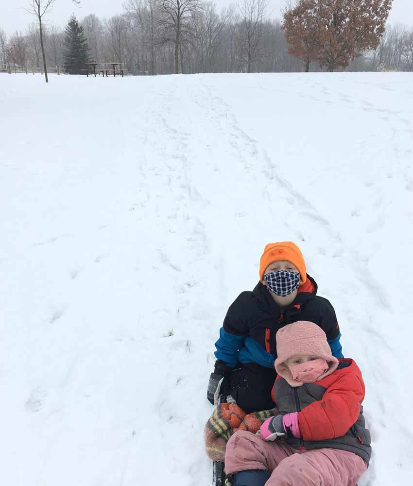 two children in a sled at the bottom of a snowy hill at Gale Woods Farm in Minnetrista