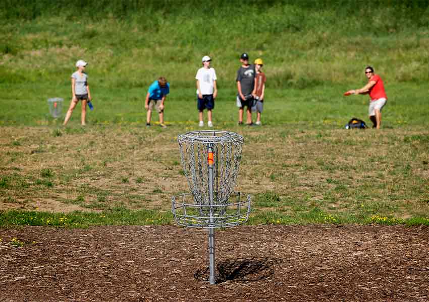 disc golf tee in foreground with players in background