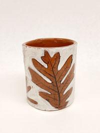 A clay cup with a leaf design.